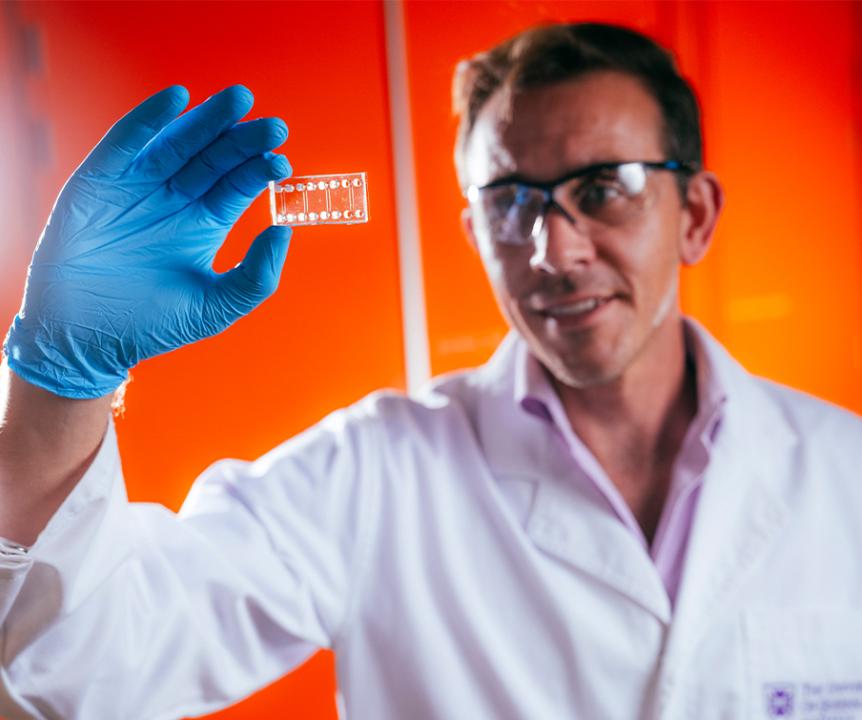 A male scientist wearing a lab coat and safety glasses.